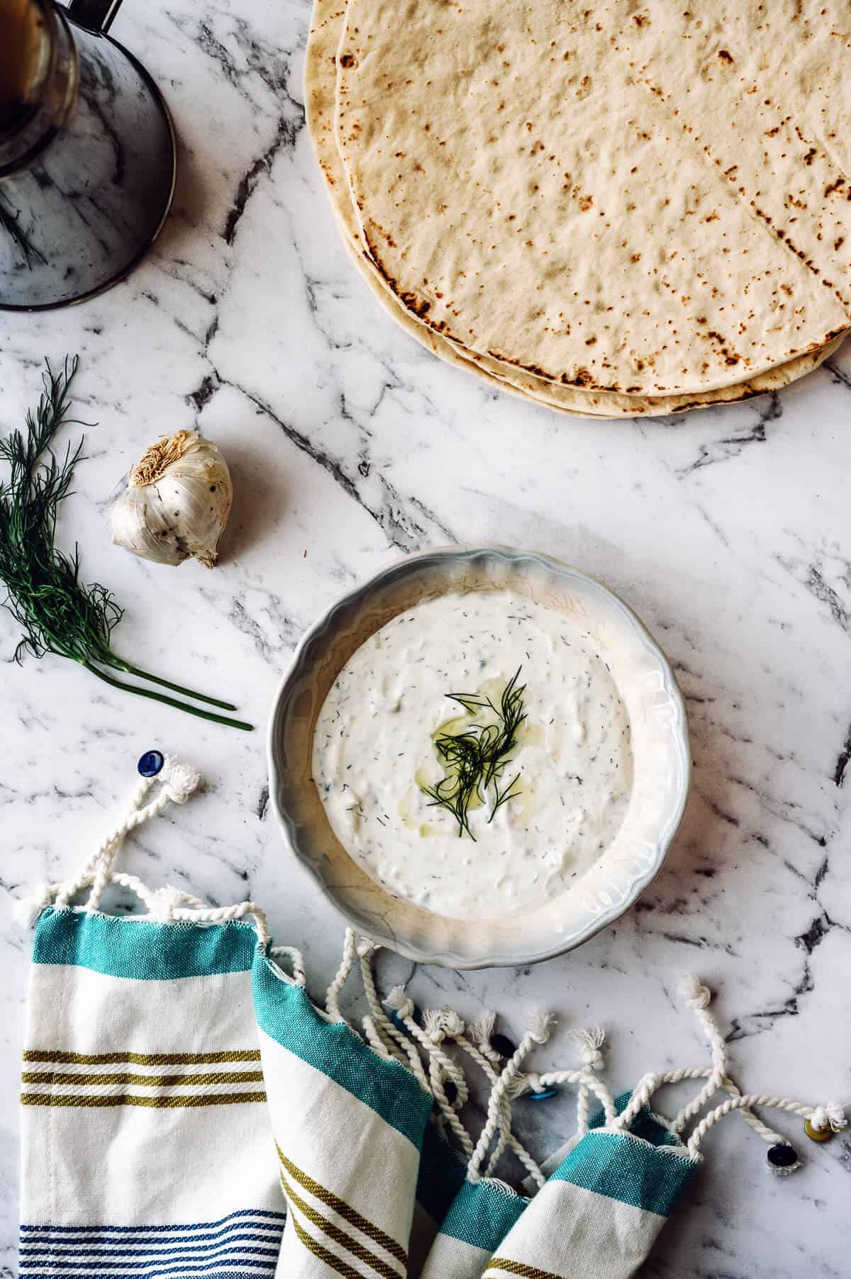 a bowl of tzatziki dip in the middle of the table served with pita bread