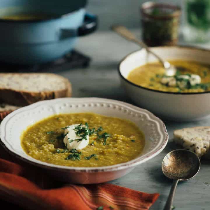 2 bowls of lentil and chickpea soup served on a grey table