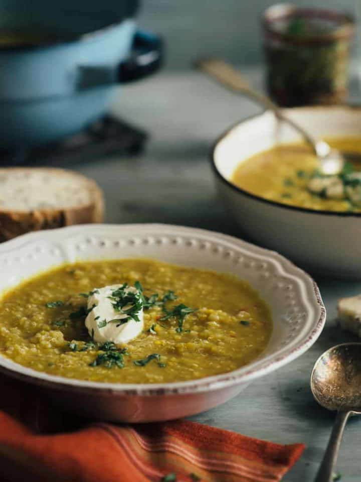 2 bowls of lentil and chickpea soup served on a grey table
