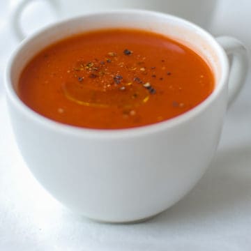 a white mug filled with tomato soup