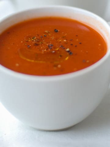 a white mug filled with tomato soup
