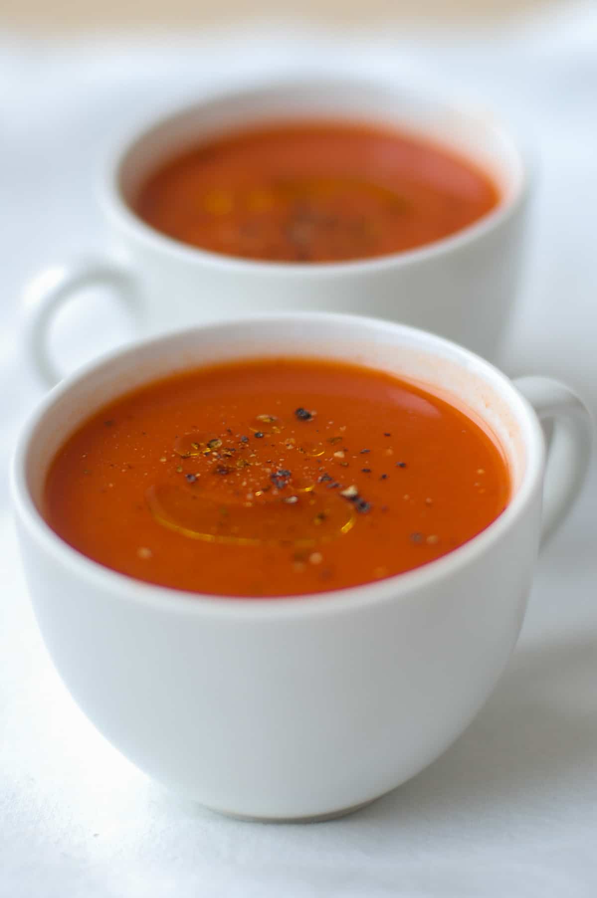 two mugs filled with tomato soup