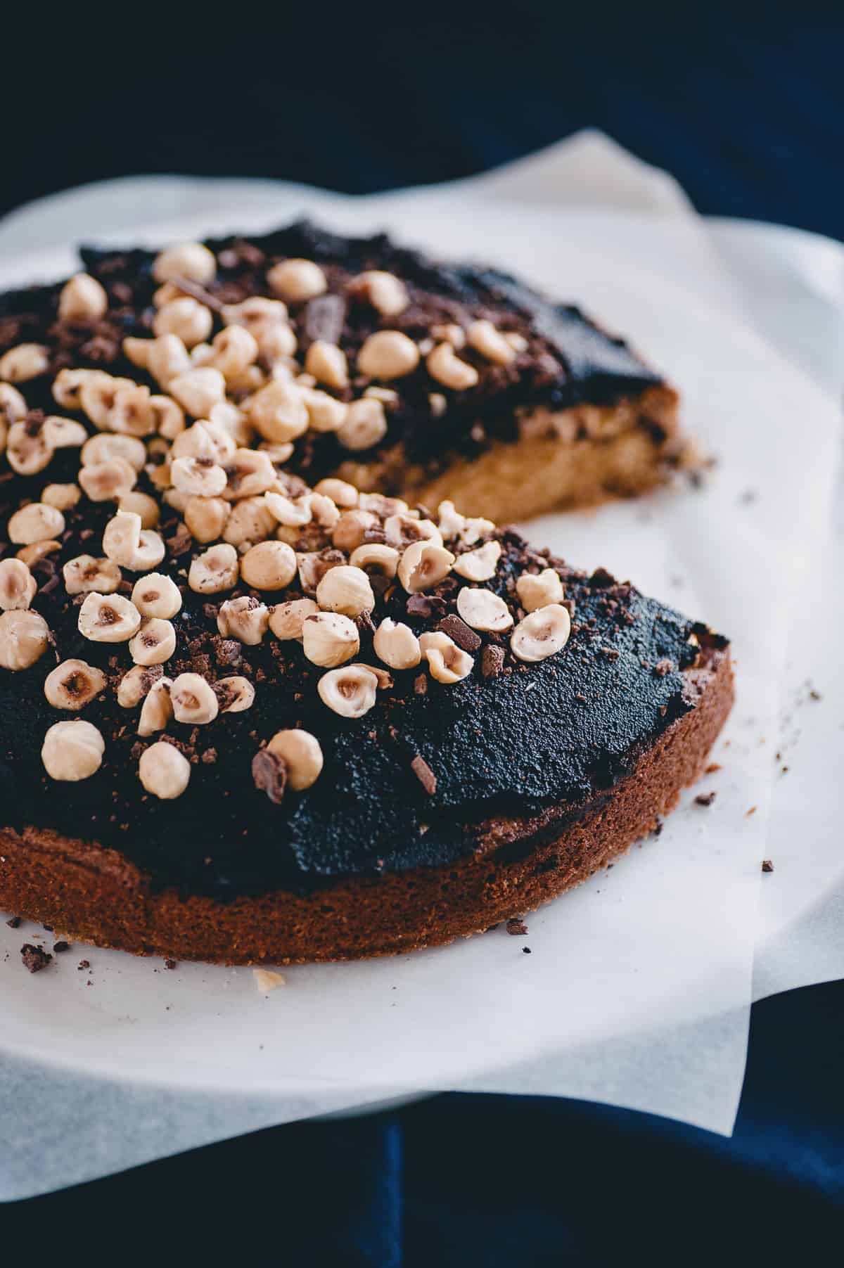 a cake topped with a chocolate spread and raw hazelnuts