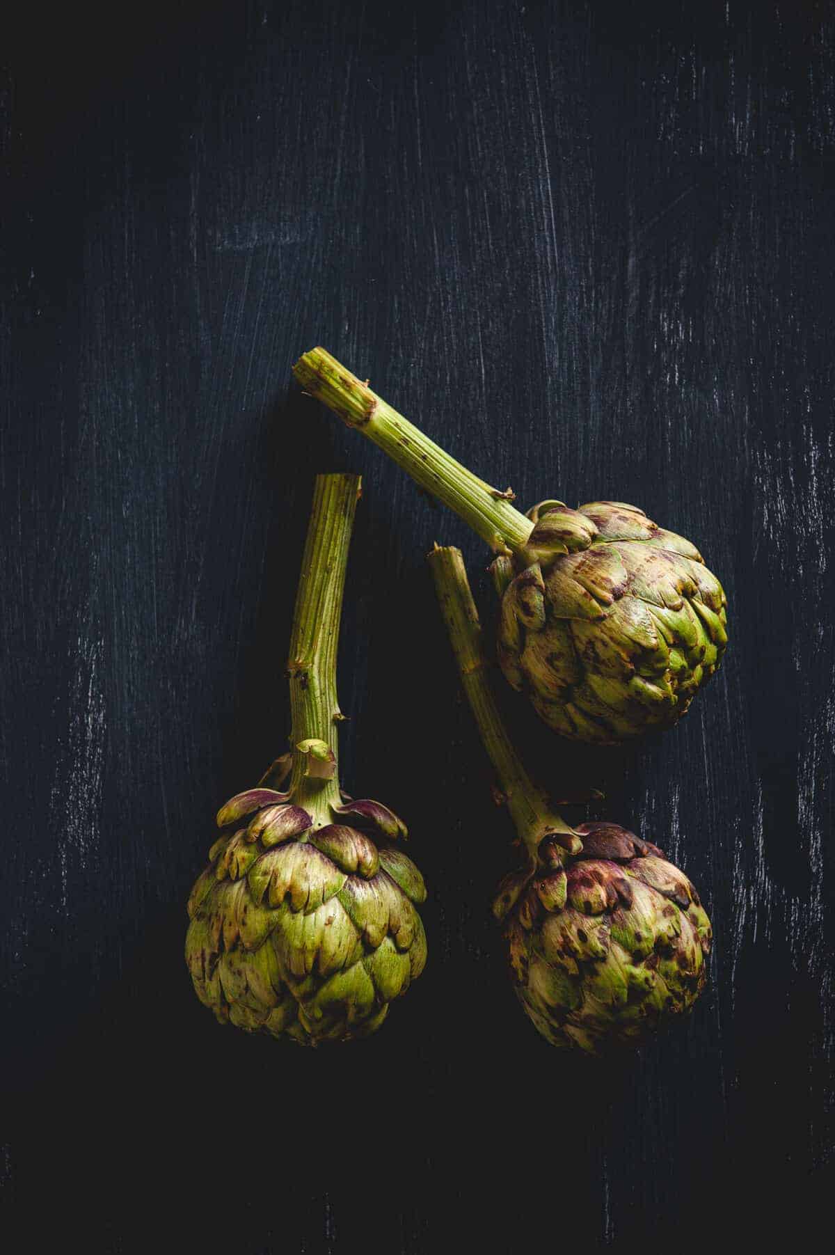 three artichokes on a table