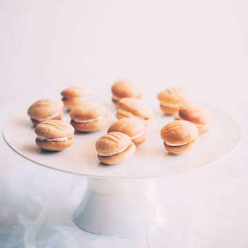 a selection of sandwiched cookies on a white cake stand