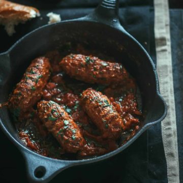 4 meatballs served in a pan with tomato sauce