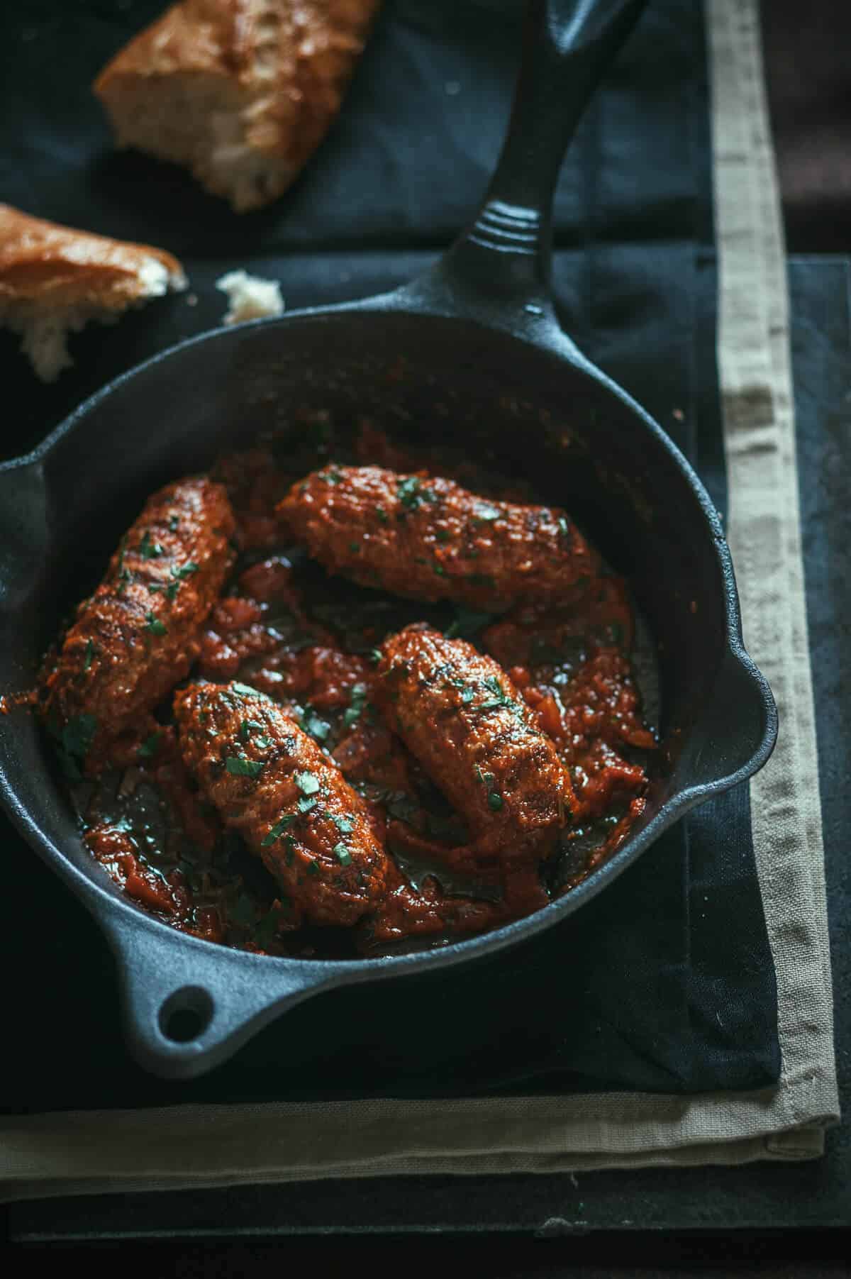 4 meatballs served in a pan with tomato sauce