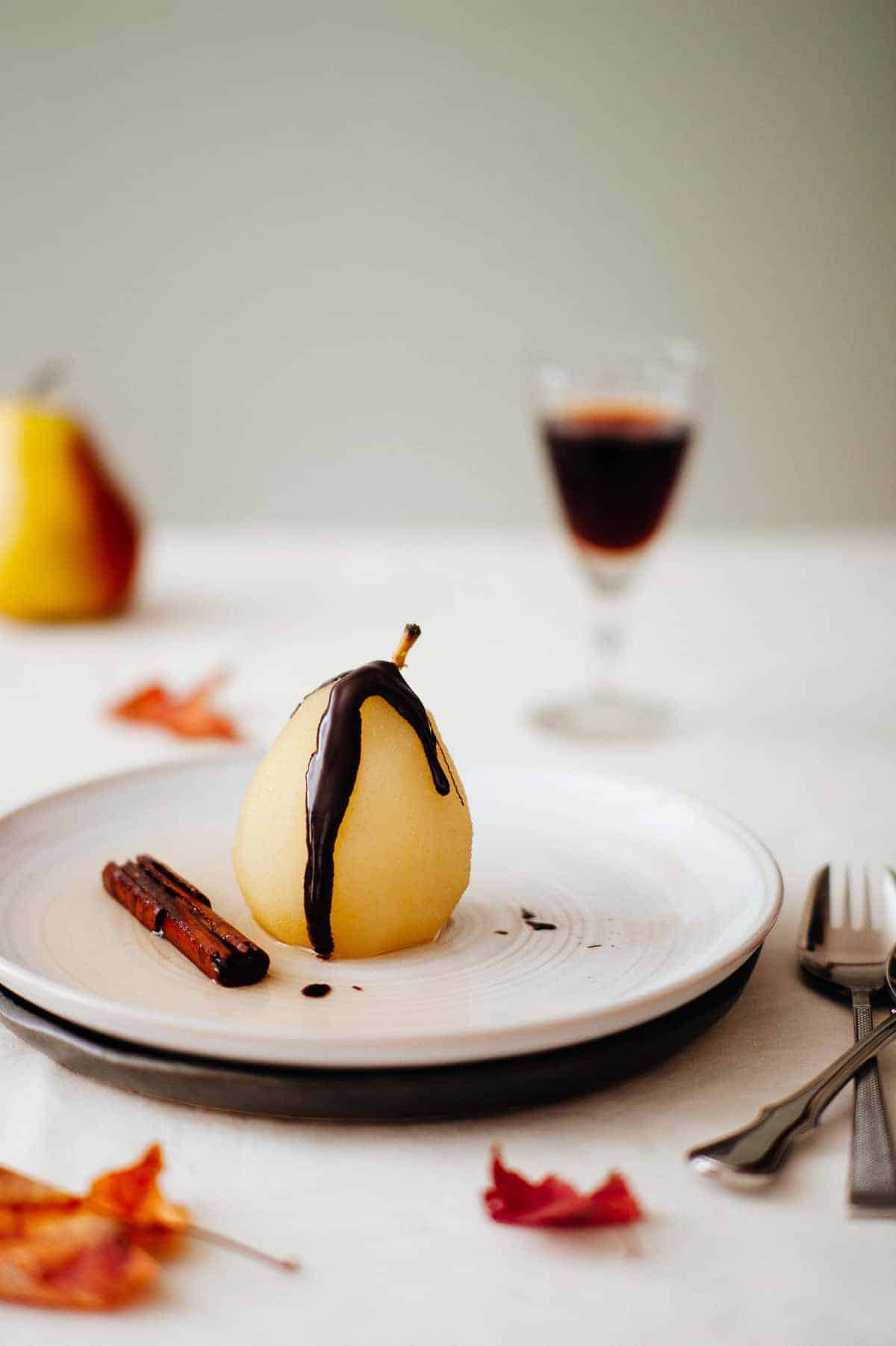 a poached pear on a plate drizzled with chocolate 