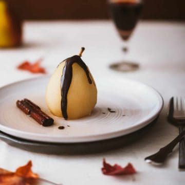 a poached pear on a plate drizzled with chocolate