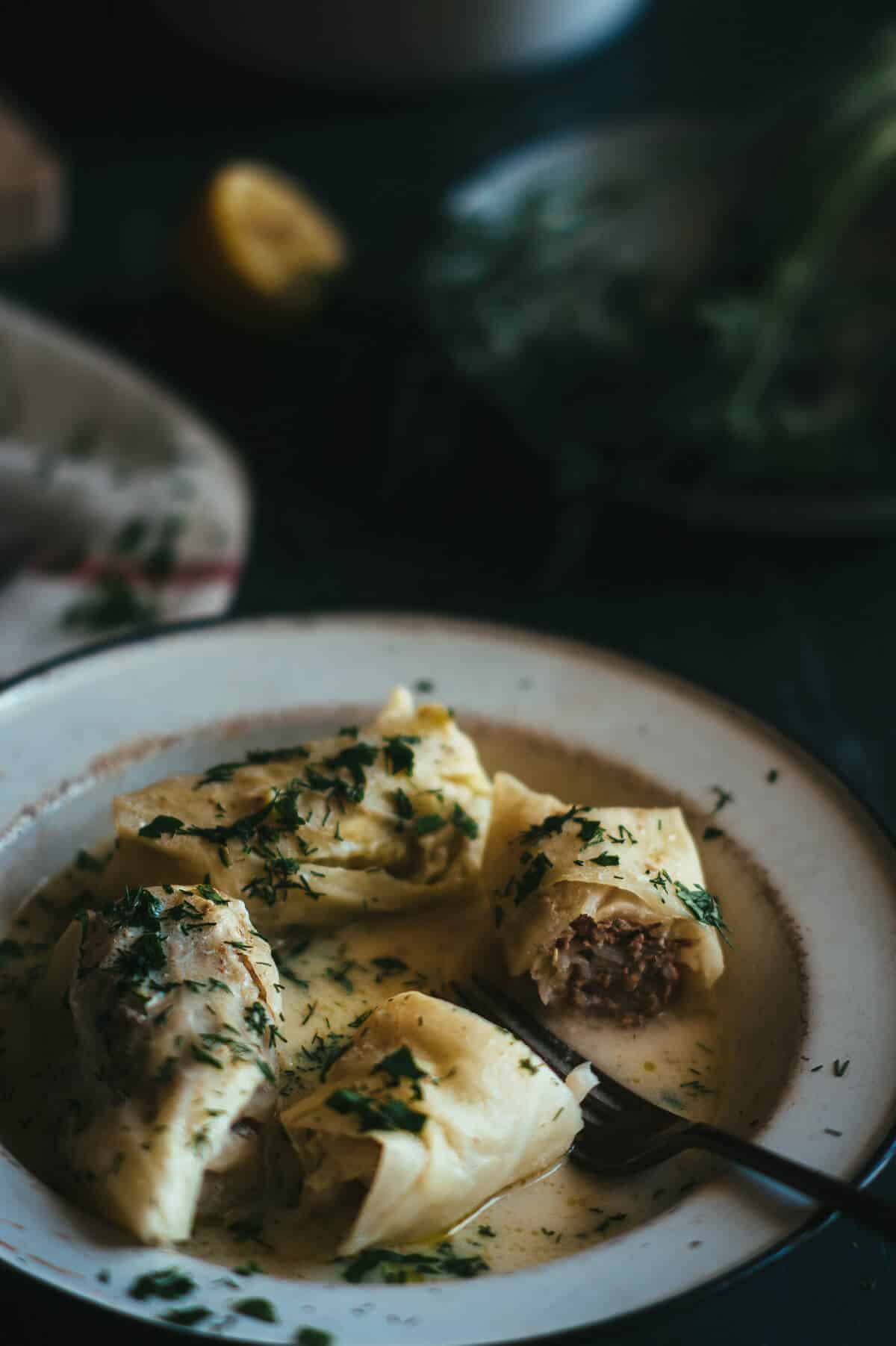 a white plate filled with rolls made out of cabbage leaves