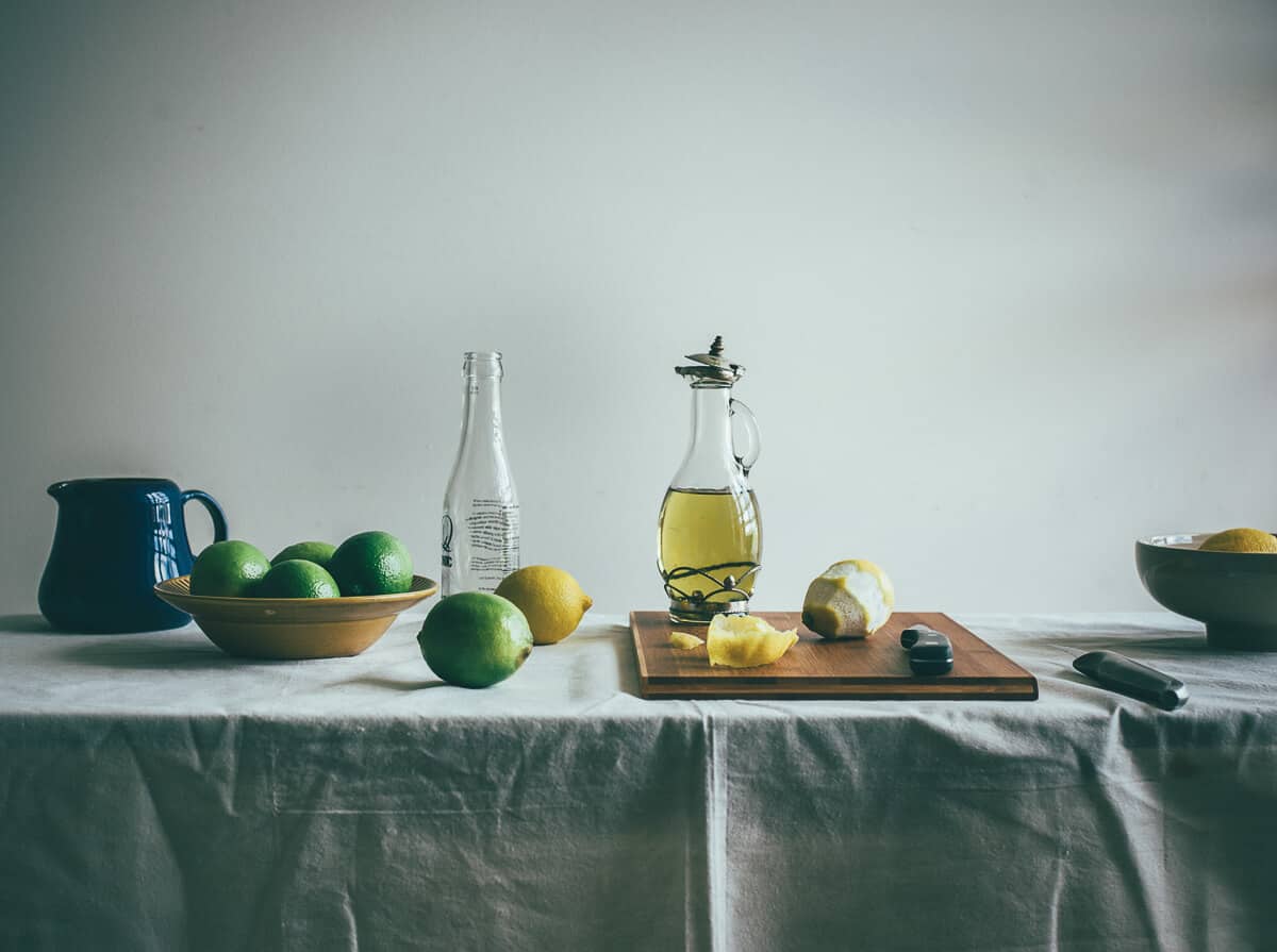 a table filled with lemons, limes and a bottle of olive oil