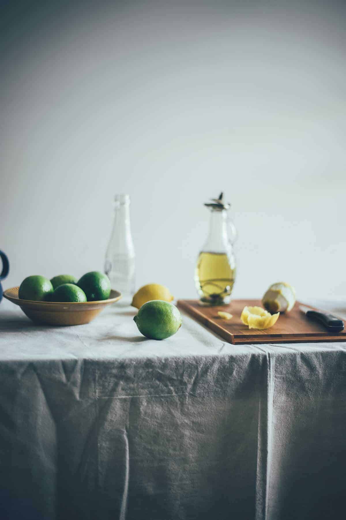 a table filled with lemons, limes and a bottle of olive oil