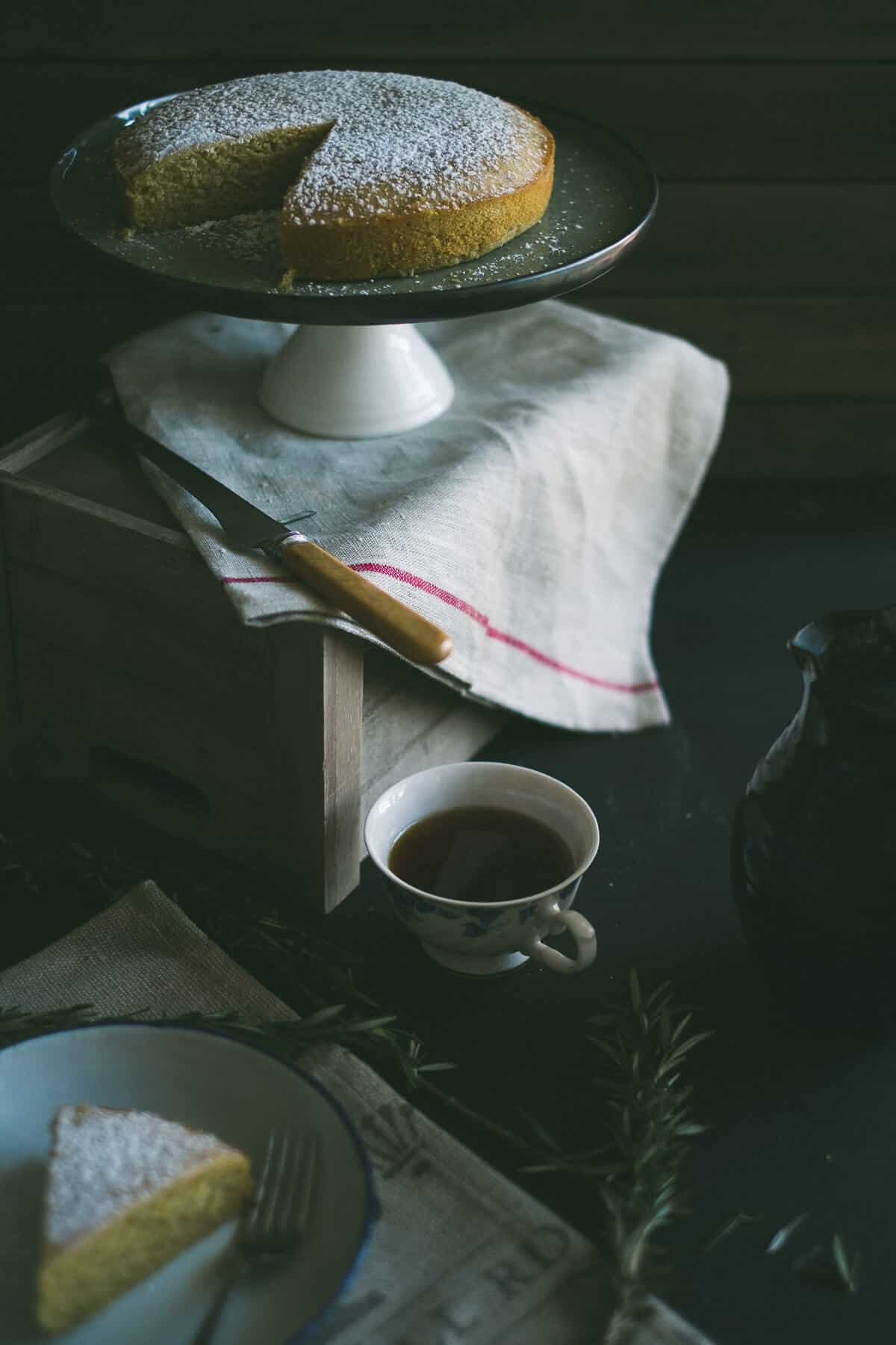 a cake on a cake stand sitting on top of a wooden box with a kitchen towel draped over it