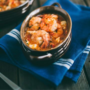 cooked prawns in a tomato sauce served in an oval ceramic dish