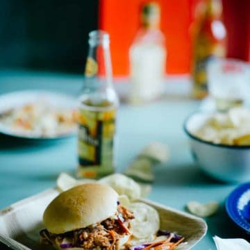 a sandwich filled with pork meat served in a bamboo plate