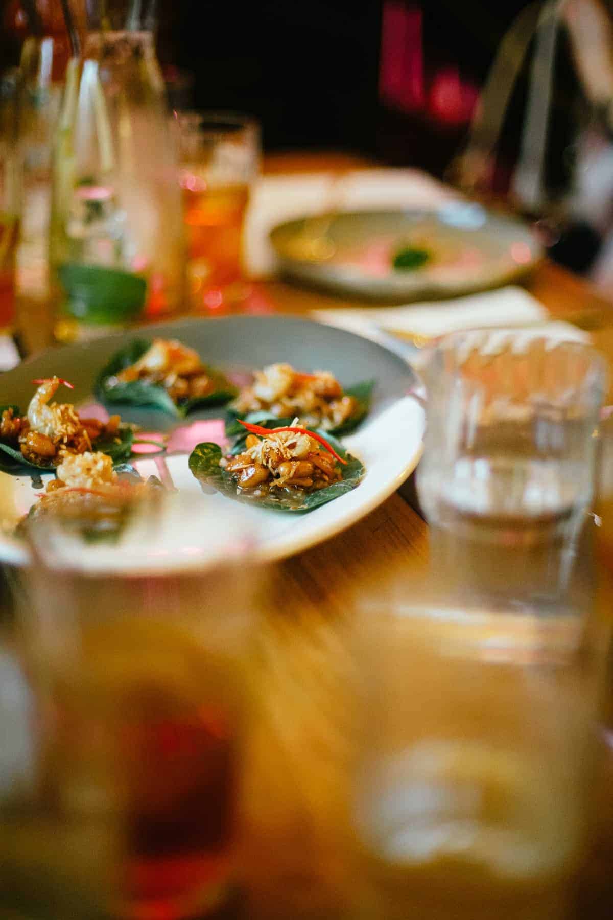 betel leaves with caramelised coconut, prawns, lime, ginger and chilli served on plate at Golden Boy restaurant in Adelaide