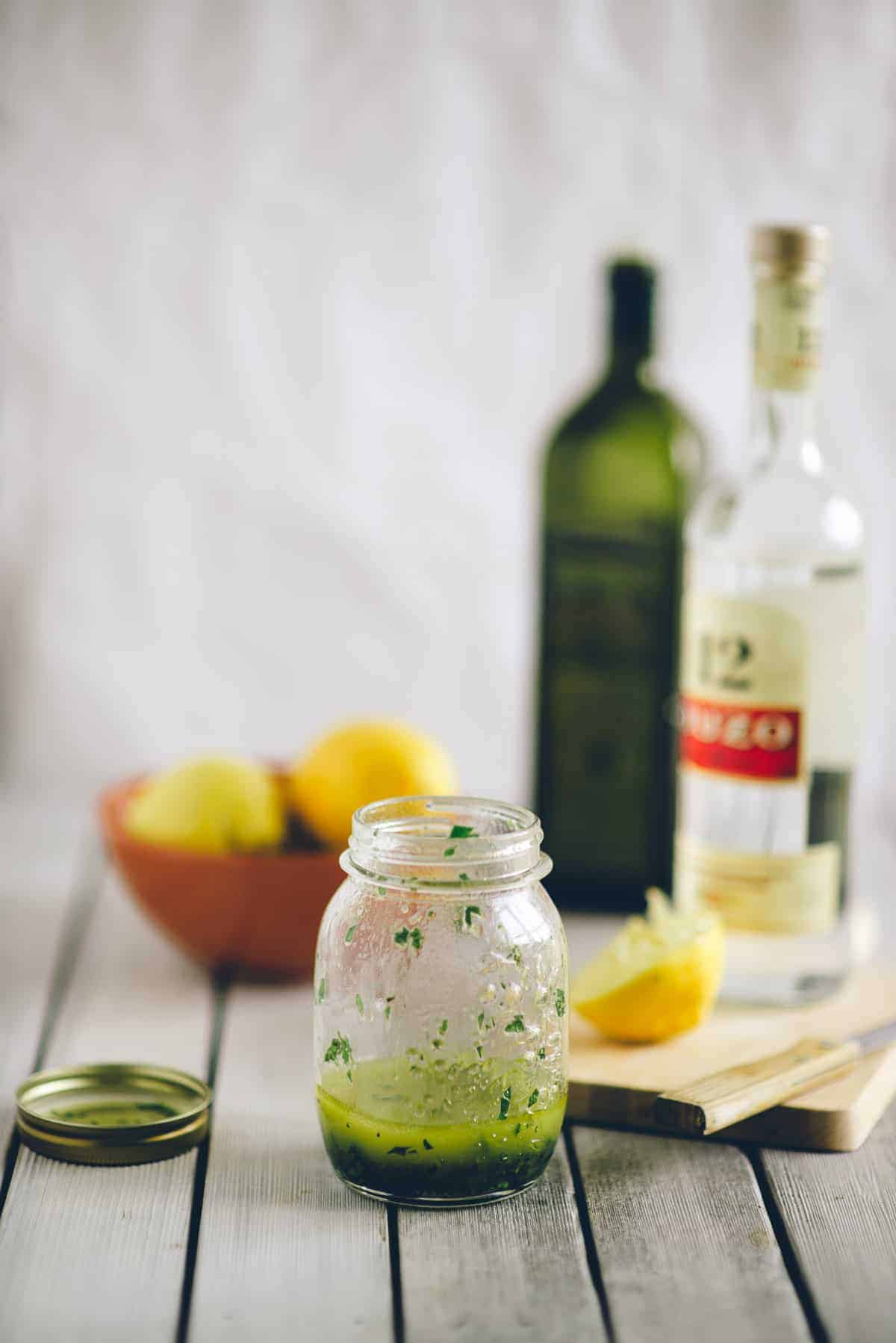 a jar of salad dressing made with ouzo on a white table