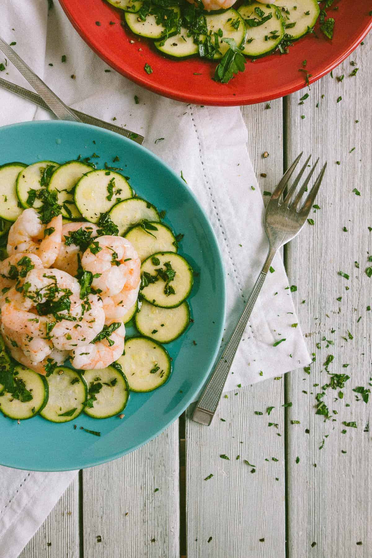 a green plate with prawns and zucchini 