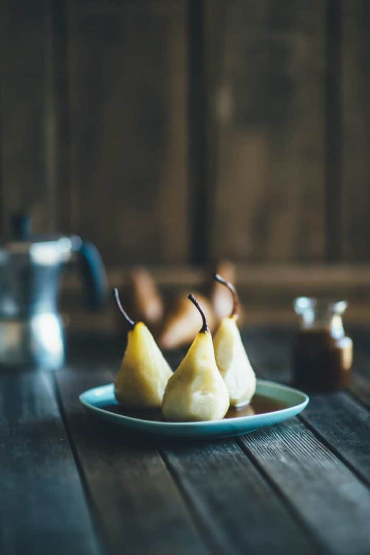three poached Beurre Bosc pears on a plate smothered with an espresso caramel