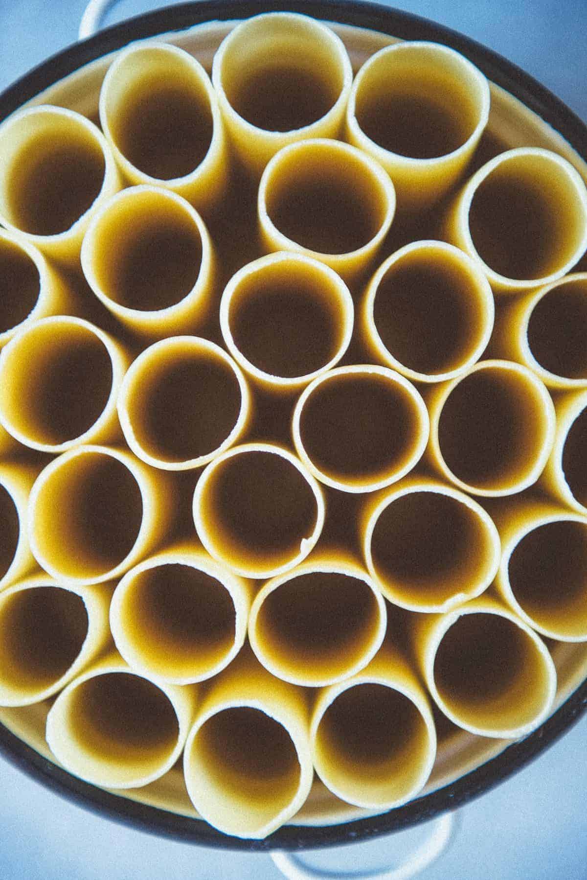 close up view of round pasta tubes stacked vertically in a baking dish