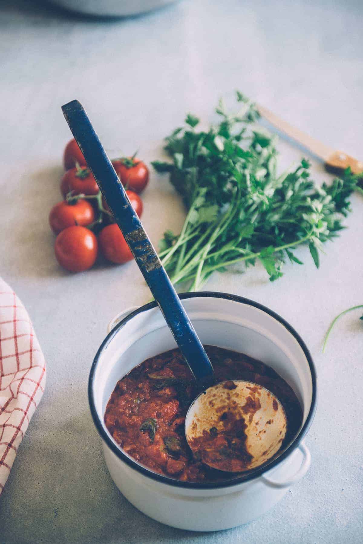 a pot with a ladle and filled with a marinara based sauce