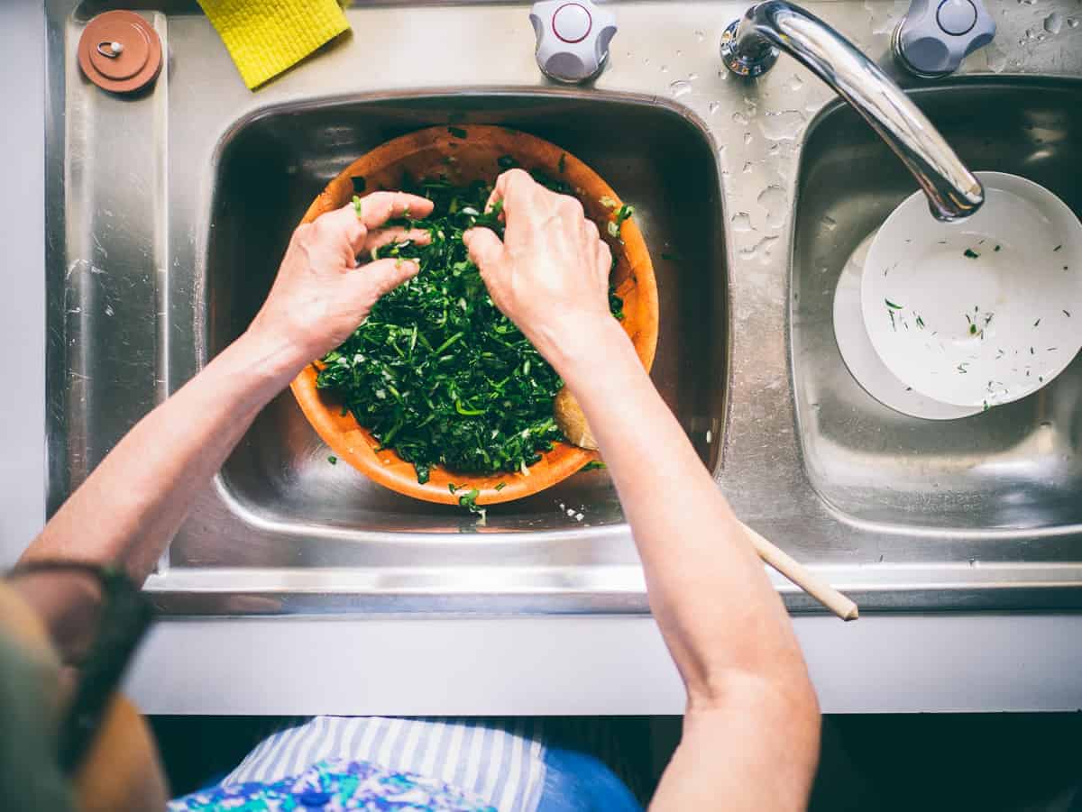 spinach being cleaned and prepped in a sink