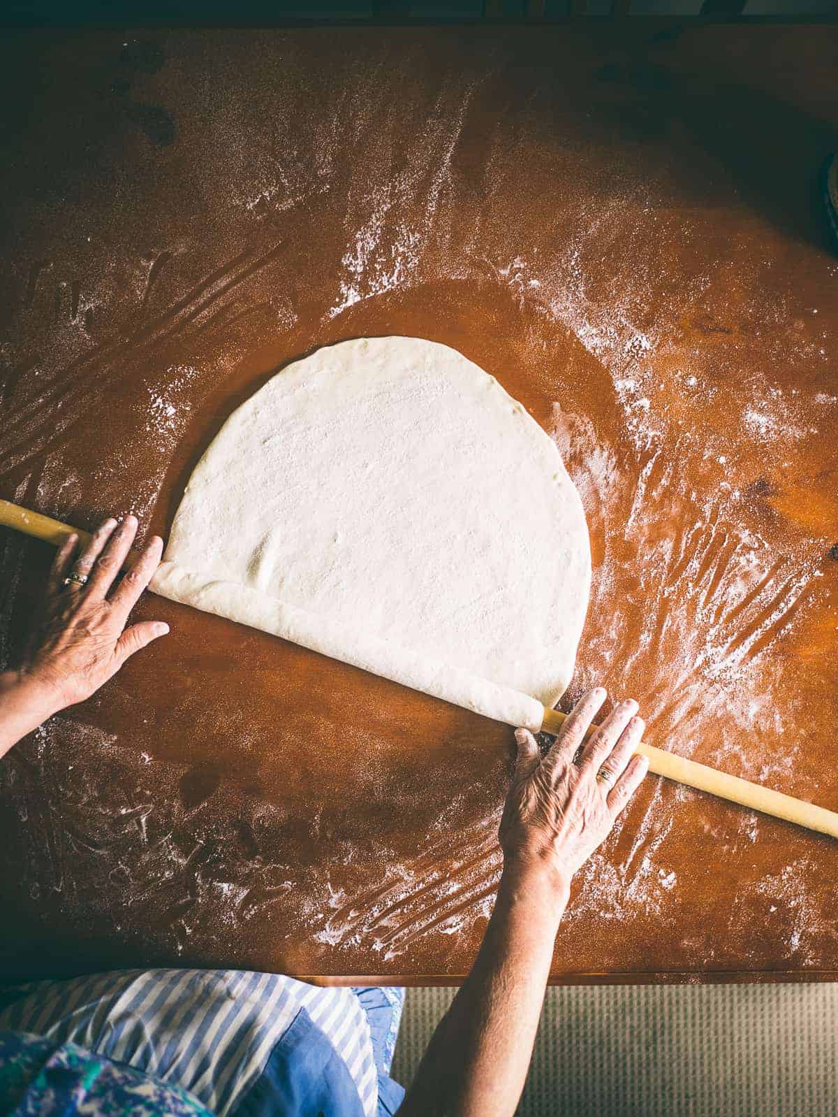 Greek mother rolling out homemade fillo dough for a Greek spinach pie