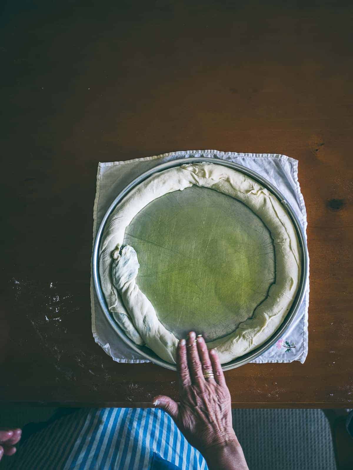 homemade spanakopita rolled out on a baking dish with olive oil