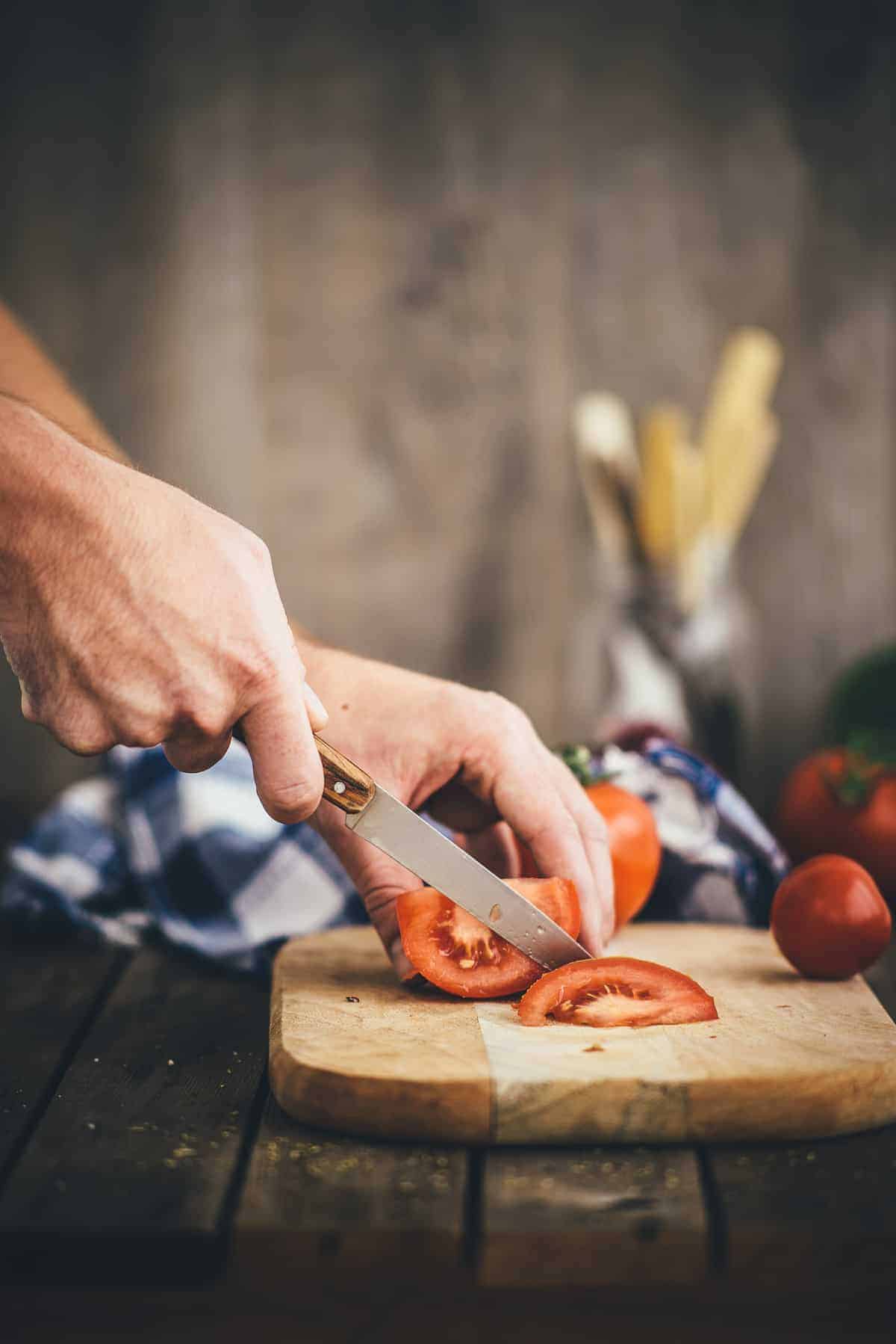 tomatoes being sliced on chopping board