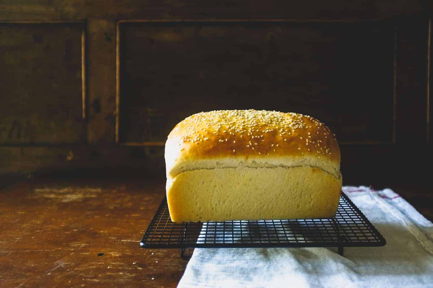 a full sized loaf of brioche bread cooling on a rack