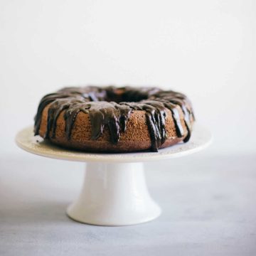 a chocolate cake with icing on a cake stand