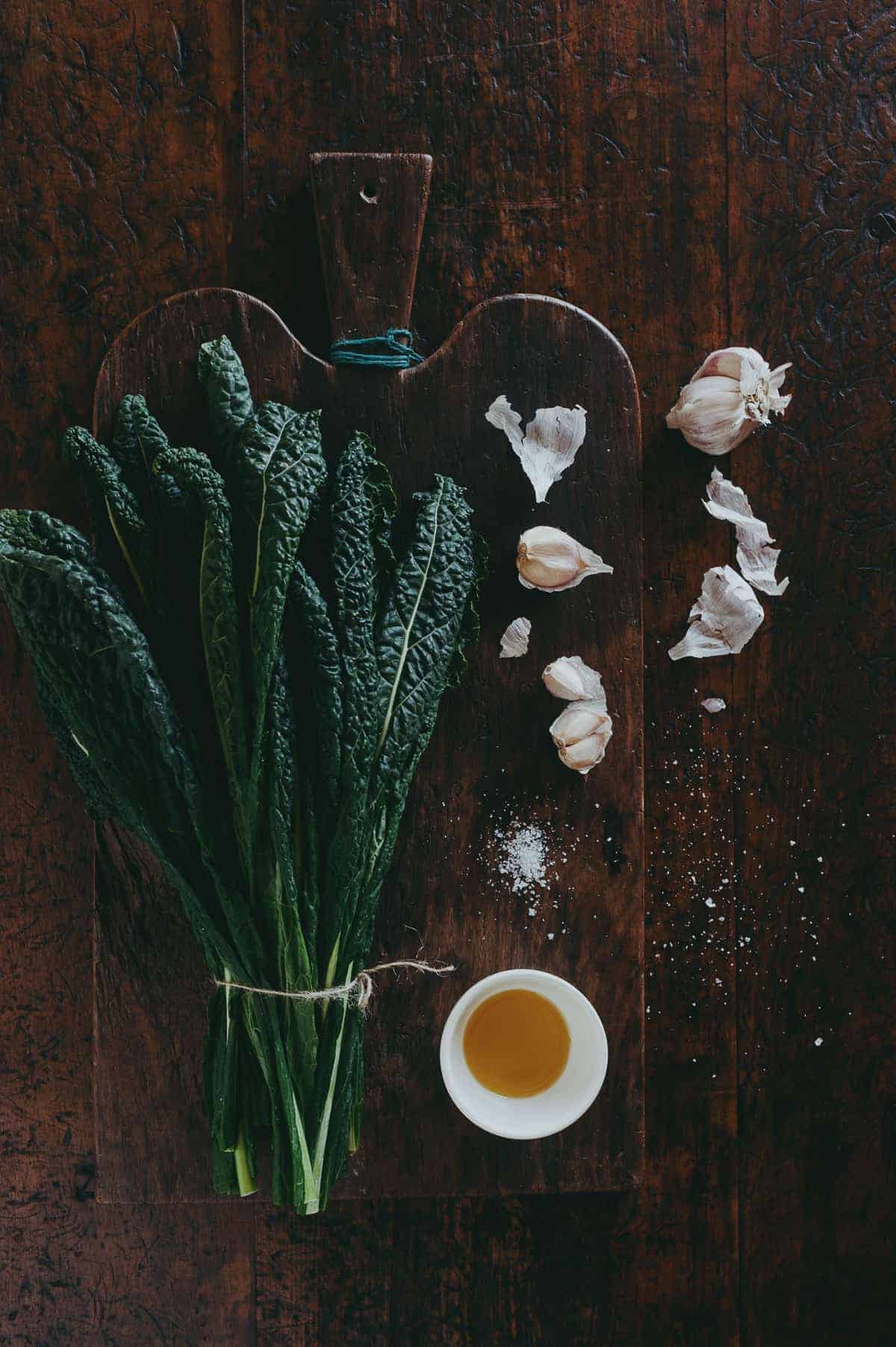 a bunch of cavolo nero leaves with garlic and olive oil on a wooden board on top of a wooden table