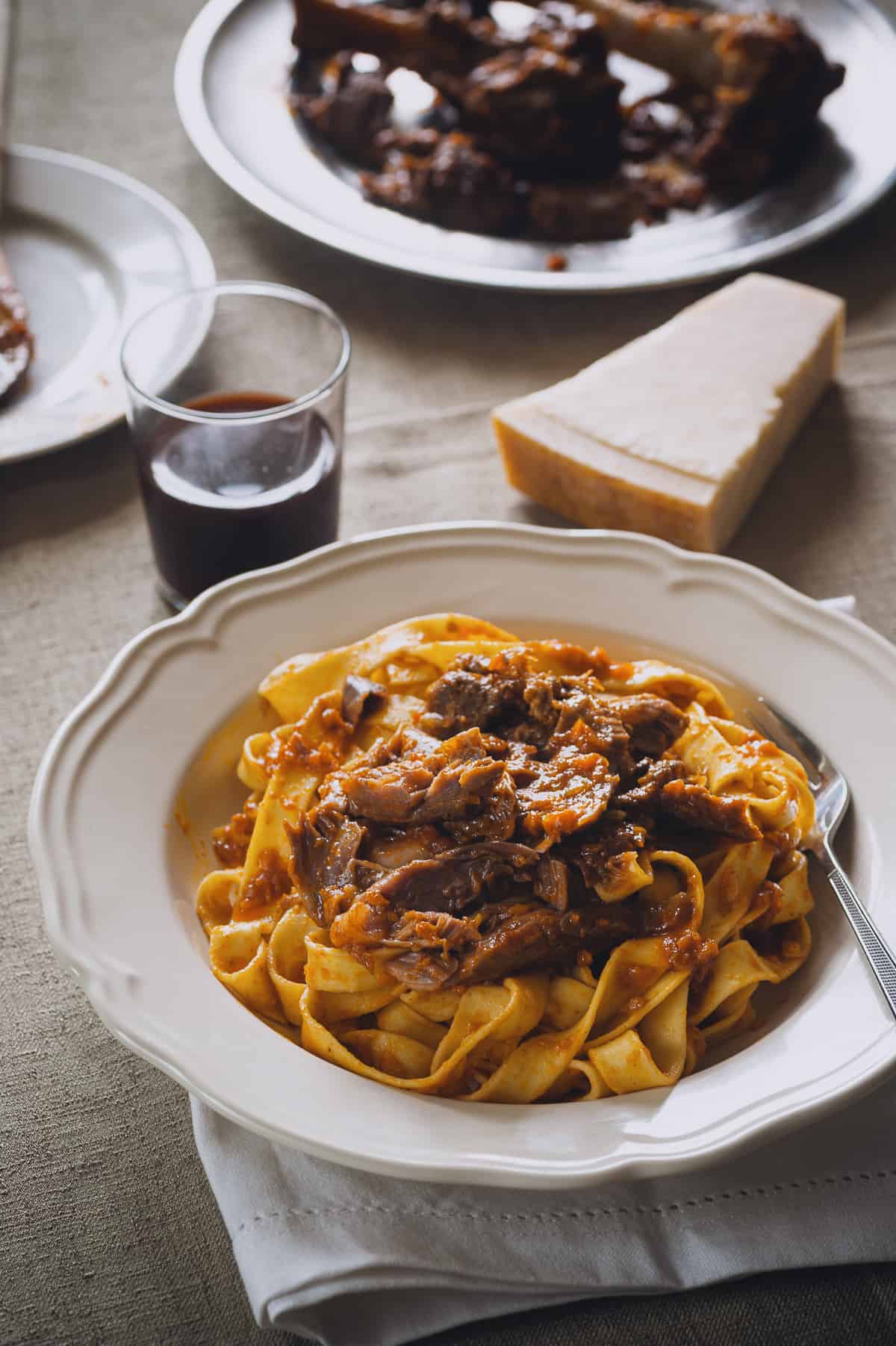 a plate of pasta topped with a meat sauce made from lamb shanks