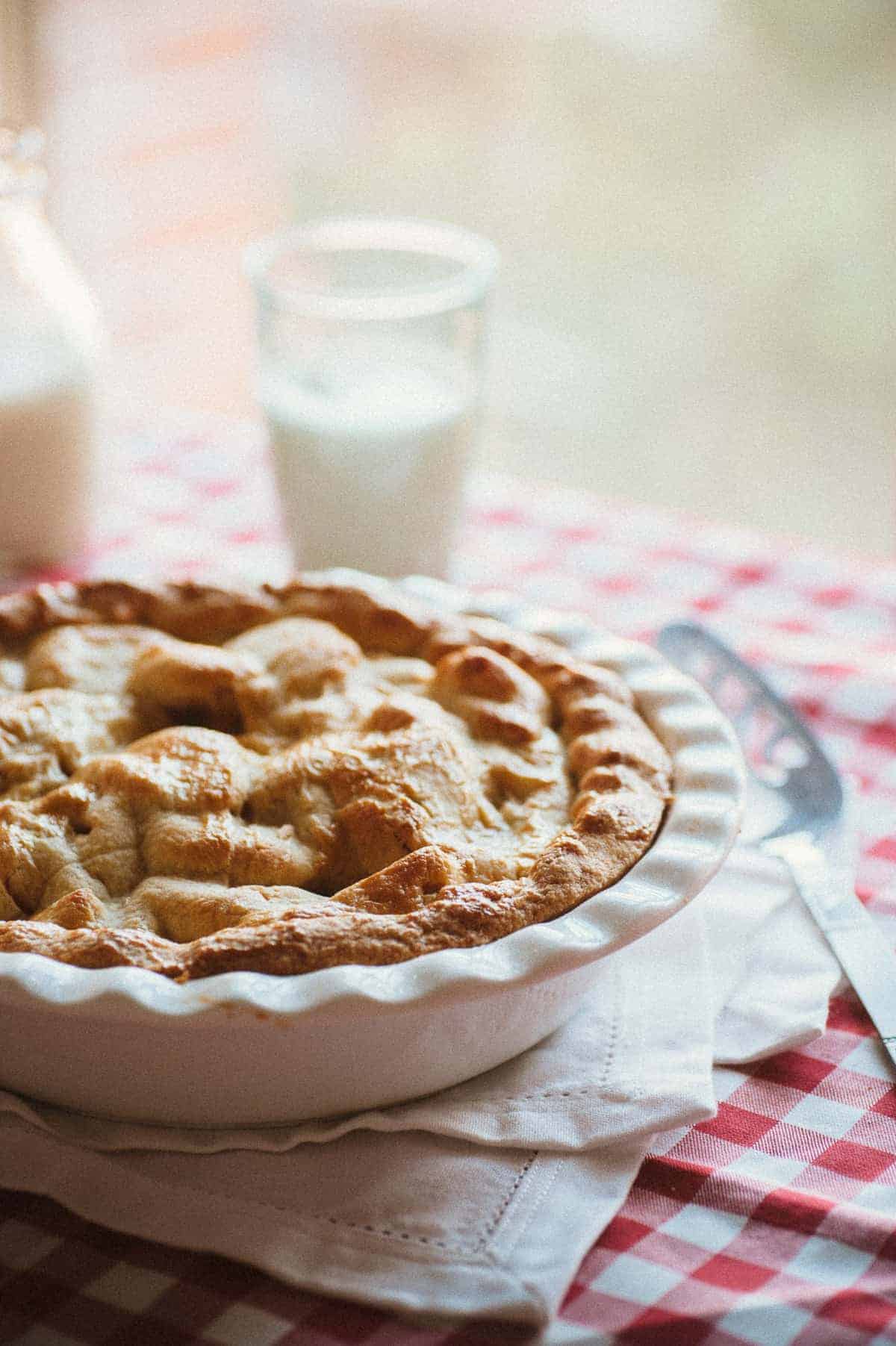 a deep dish apple pie served a red and white tablecloth