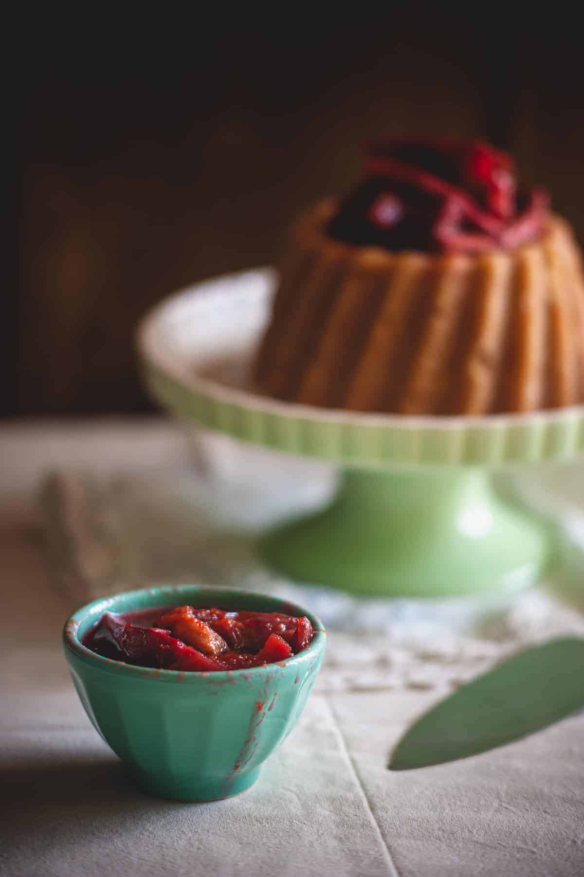 a small bowl of rhubarb compote placed in front of a cake stand holding a Greek dessert called halva