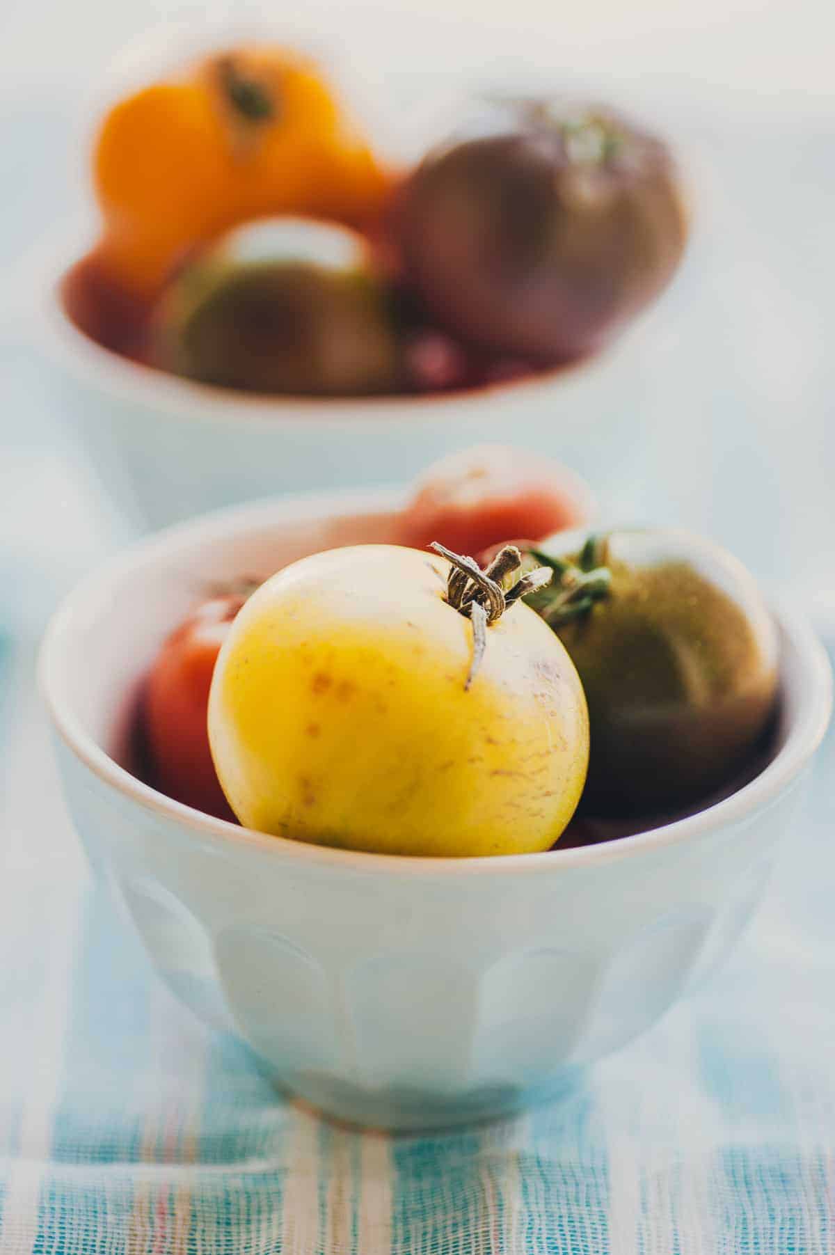 a light blue bowl filled with a variety of coloured tomatoes