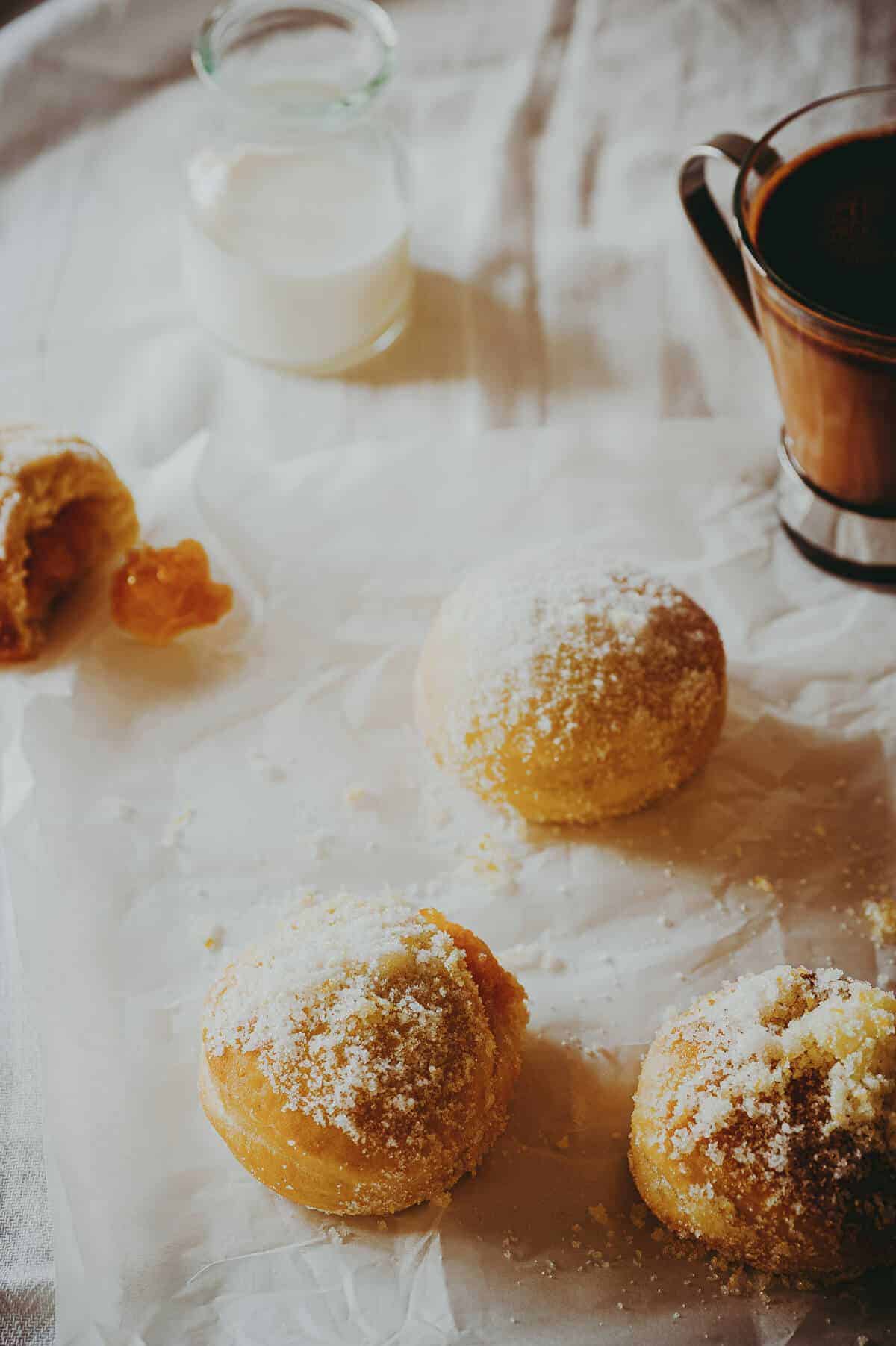 jam doughnuts covered in sugar served with a cup o f hot chocolate