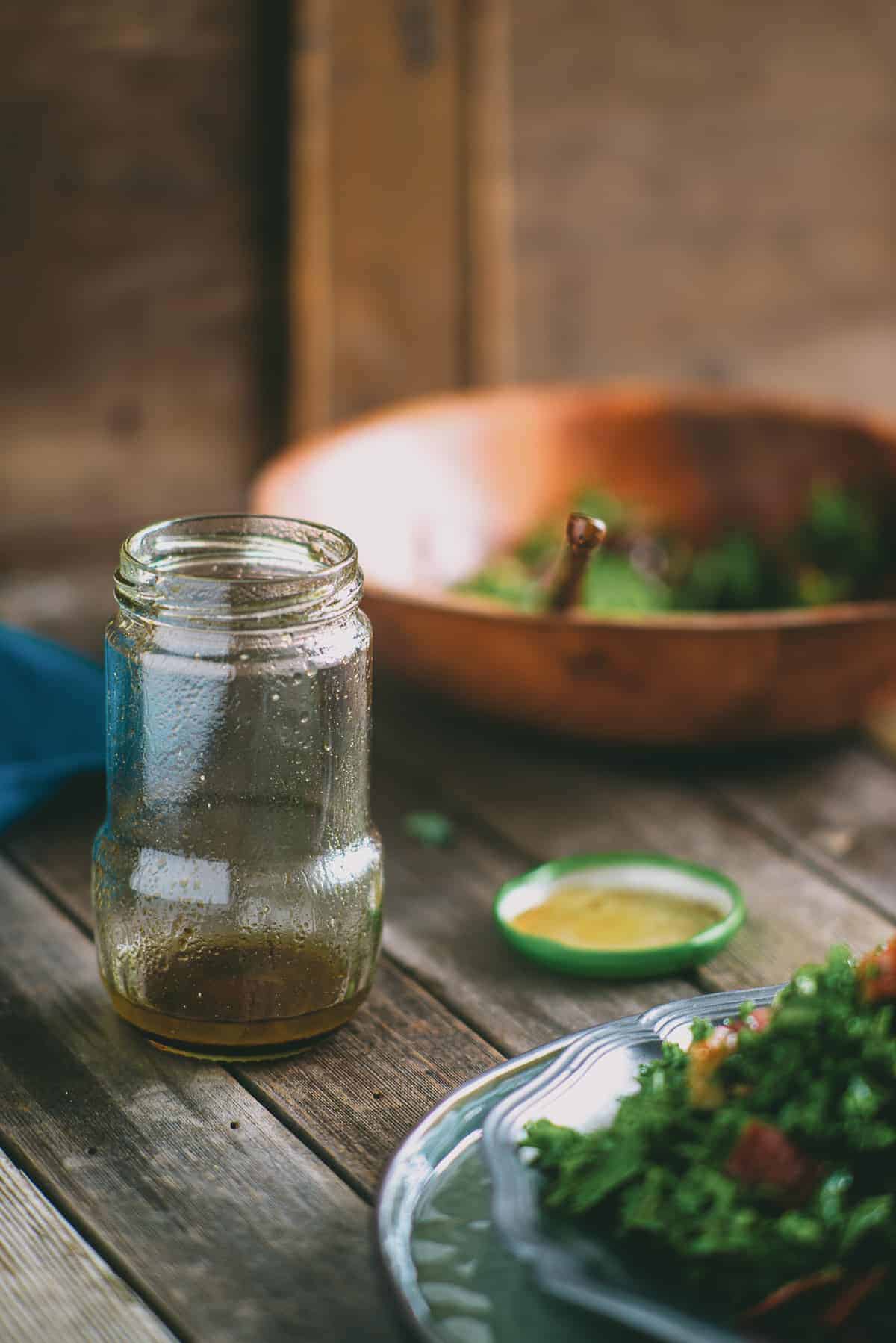 a half used jar of salad dressing on a table with a bowl of salt next to it