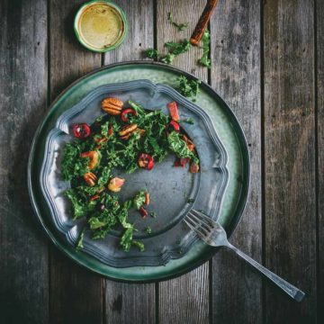 a birds eye view of a kale salad served on a silver plate on a wooden table