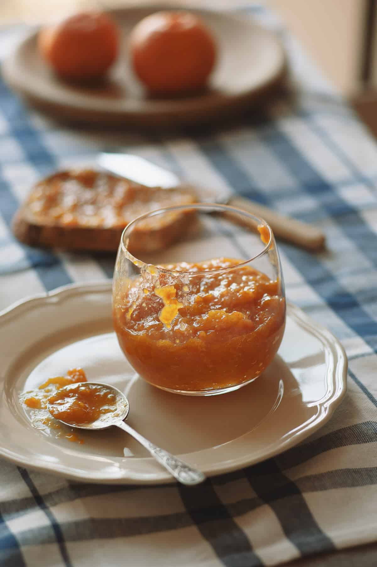 a glass filled with mandarin marmalade on a white table