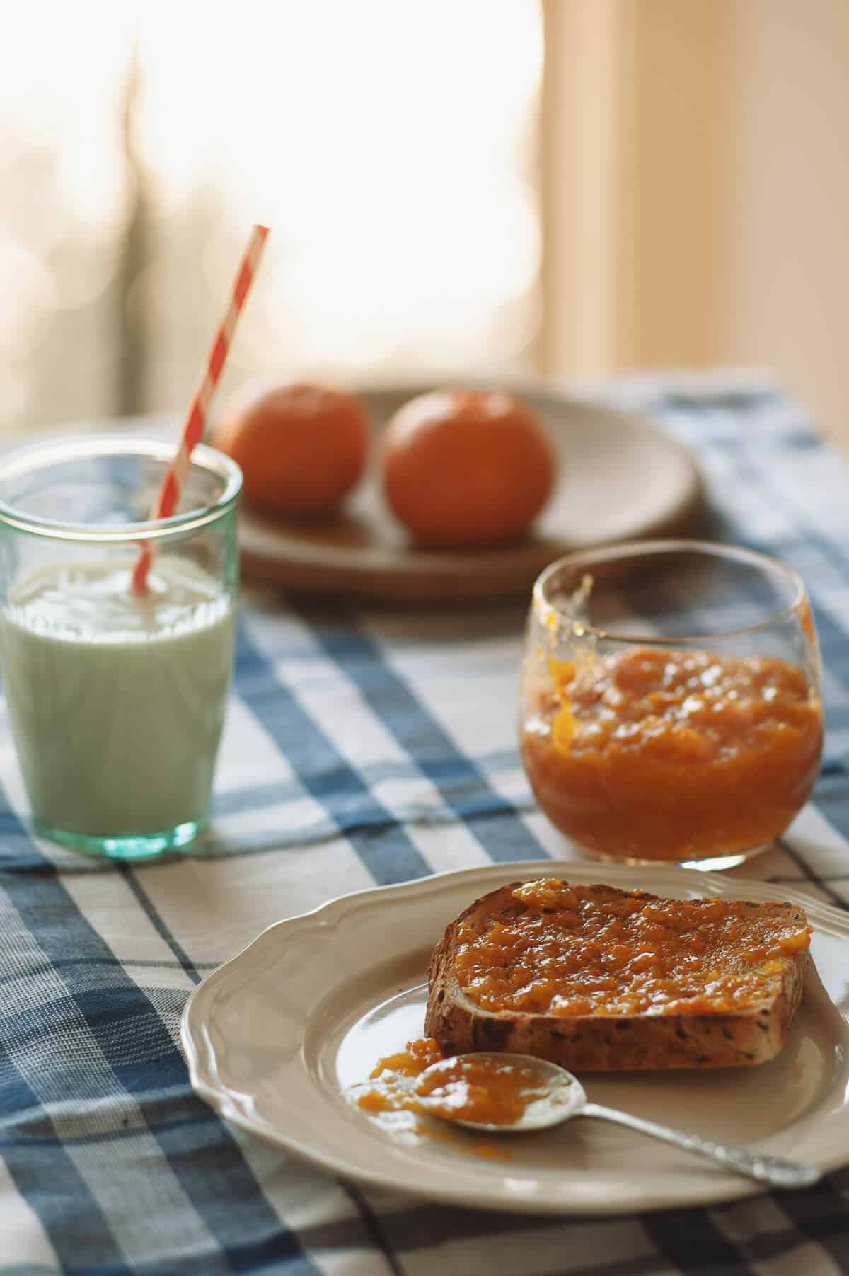 a slice of toast with mandarin jam served on a plate with a glass of milk