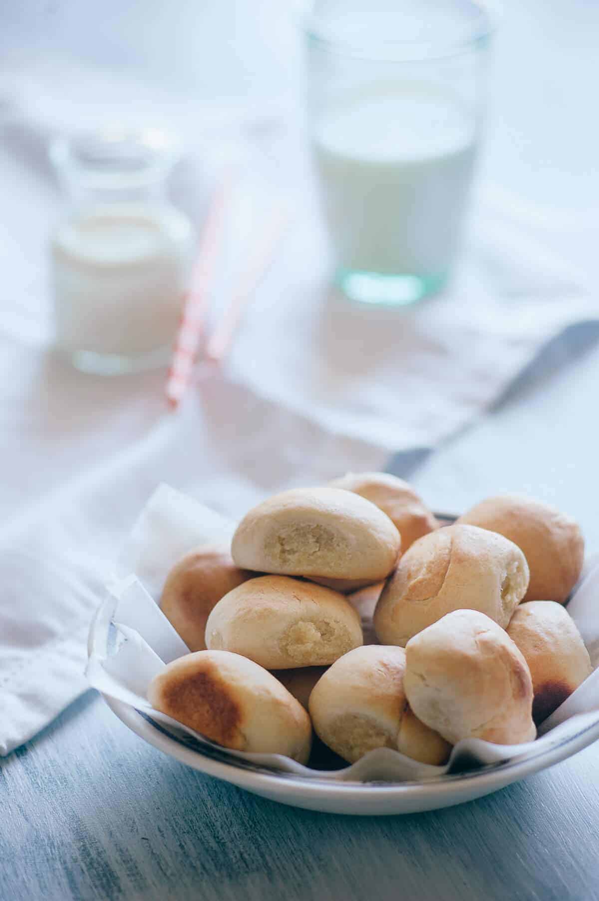 a bowl of homemade sweet bread rolls on a light blue table