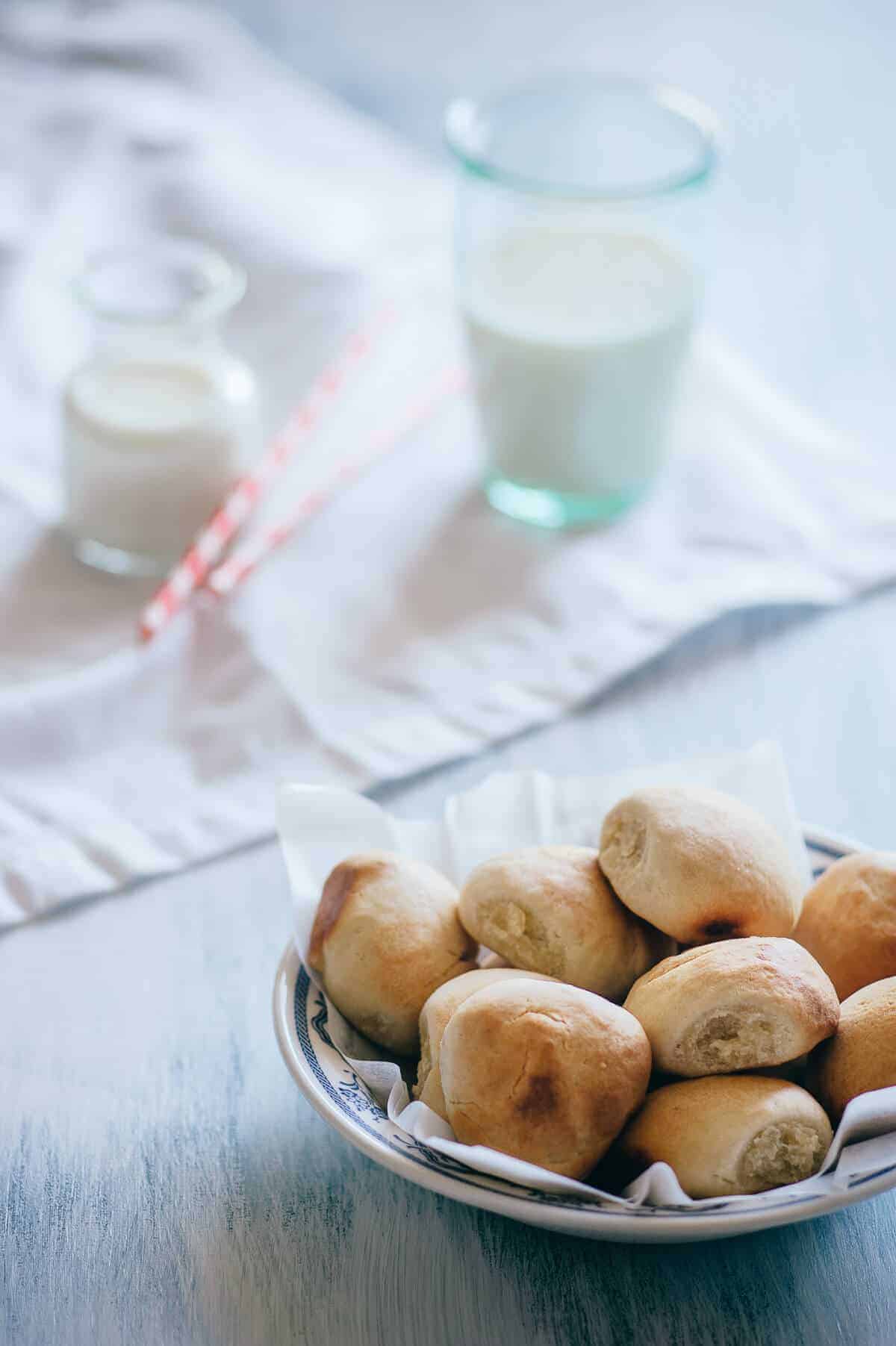 a bowl filled with bread rolls on a light blue table