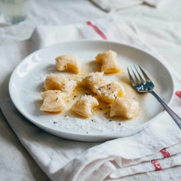 a served o ricotta gnocchi on a white plate with melted butter