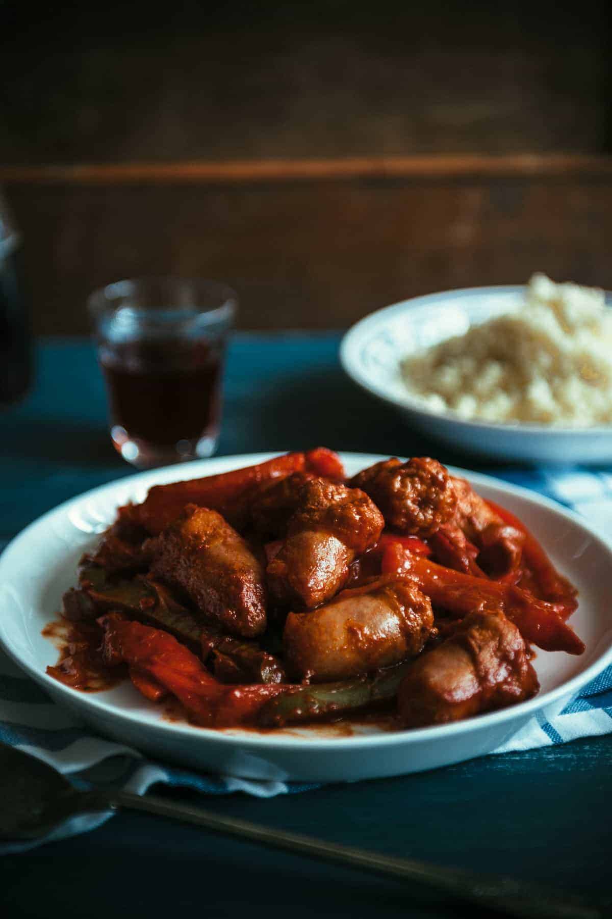 a plate filled with sausages and peppers cooked in a tomato sauce