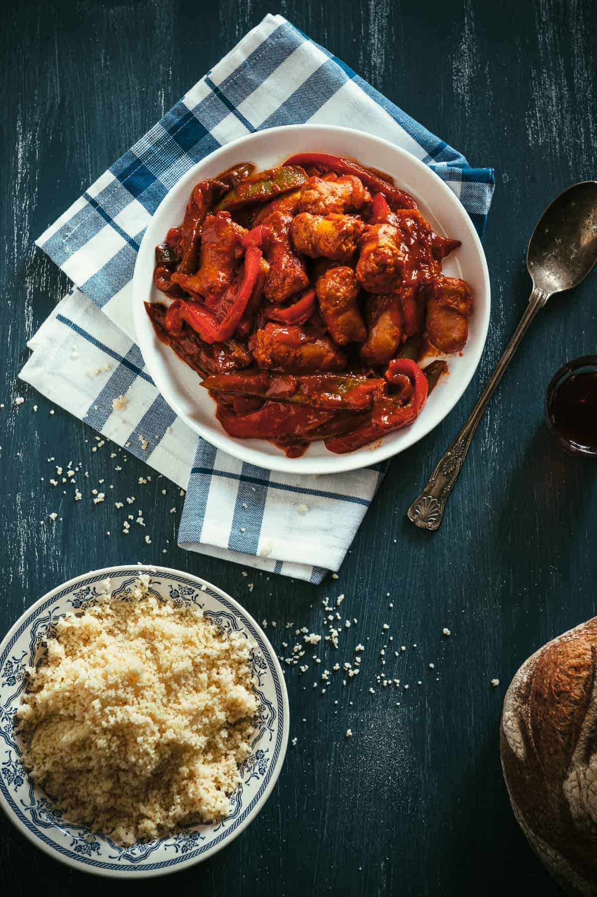 a top down view of a a plate filled with sausages and peppers cooked in a tomato sauce