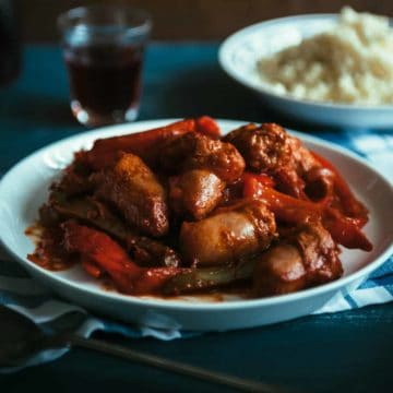 a plate filled with sausages and peppers cooked in a tomato sauce