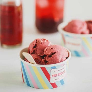 close up of small tub of ice cream with two red drinks in the background