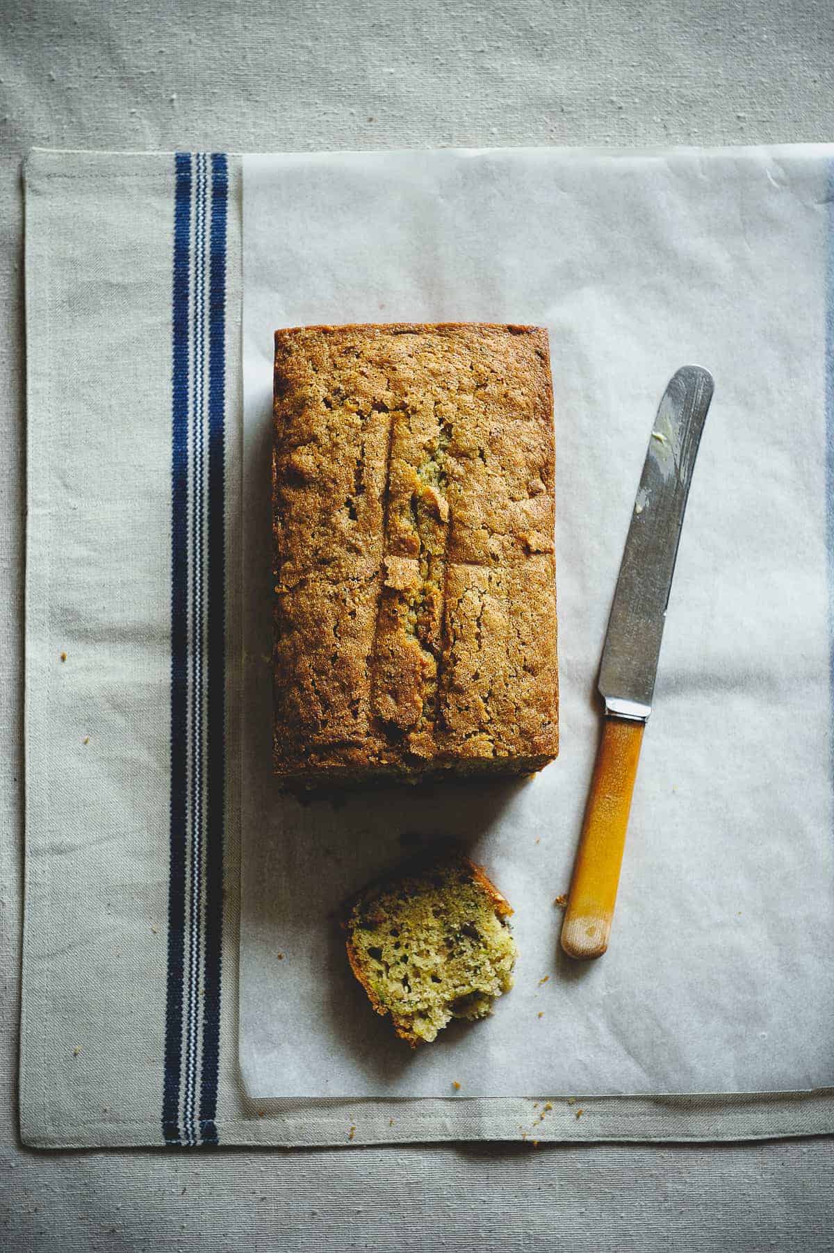 top down view of a zucchini bread on a table with a knife next to it