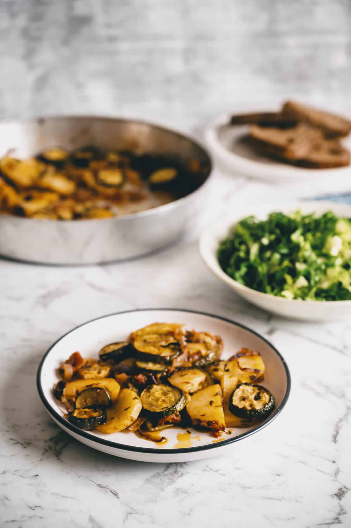 a plate filled with roasted vegetables accompanied by a tray of roasted vegetables and a green salad